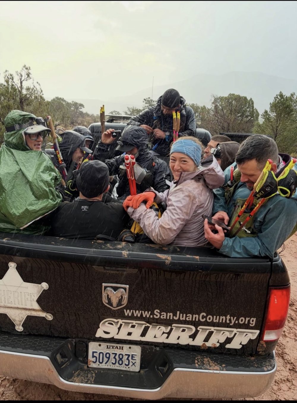 Runners and pacers in rain gear loading into the bed of a San Juan County Sheriff's truck